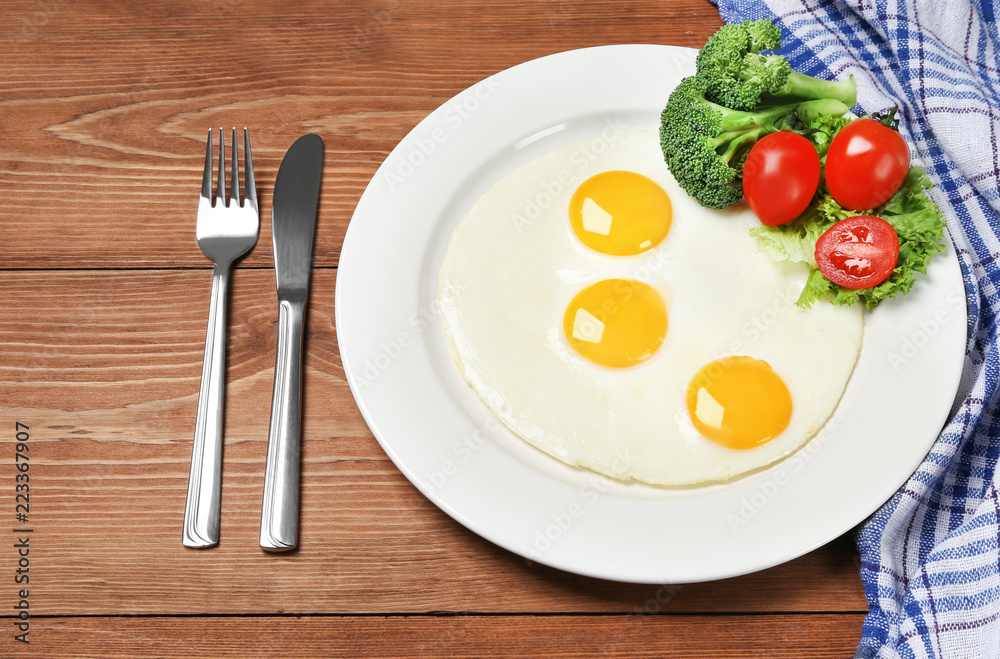 Fried eggs with vegetables on the wooden table Fried eggs with vegetables on the wooden table