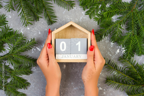 Female hands hold the Christmas calendar, 1 january on grey cement table with decoration photo