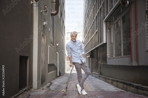 Mature man with longboard in an alley photo