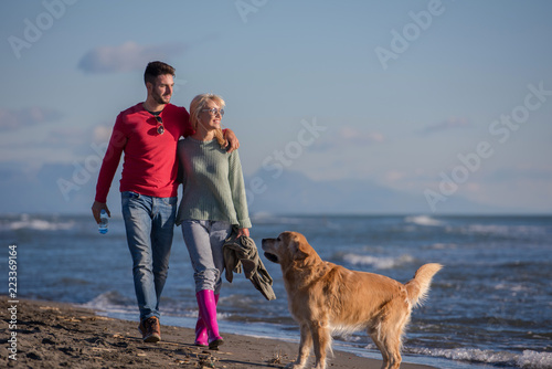 couple with dog having fun on beach on autmun day