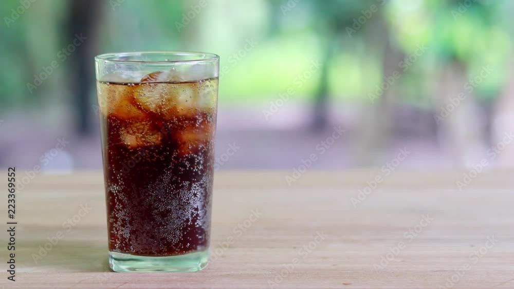 Refreshing black soda soft drinks or cola with ice in a clear tall glass with nature background. Refreshing black soda soft drinks or cola with ice in a clear tall glass with nature background.