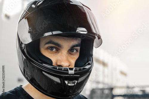 Close up portrait of biker in black glossy helmet on urban background.