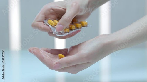 Female hand take medicaments dose. Close up of woman pour tablet from blister. Prescription drugs in woman hand