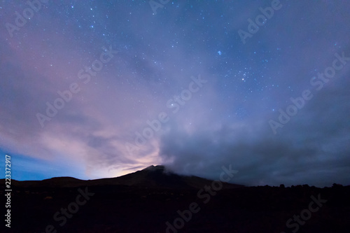 Vulkan unter Sternen und Wolken bei Nacht