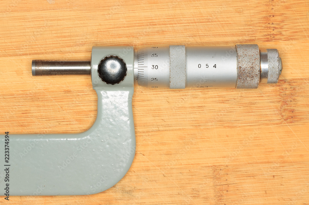 micrometer lying on a wooden Board / old-style measuring device