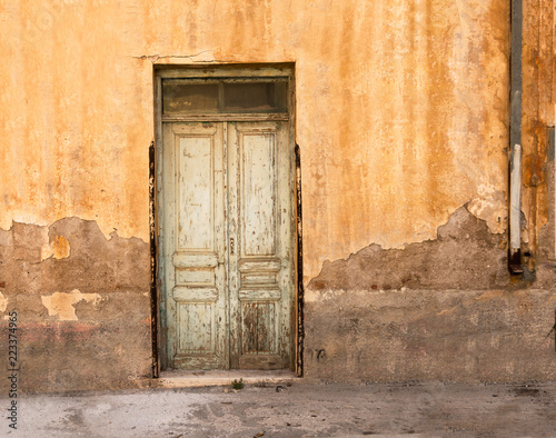 Old wooden door on grunge weathered wall. © okolaa