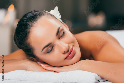 Quadro su tela young woman with flower in hair sleeping at spa salon