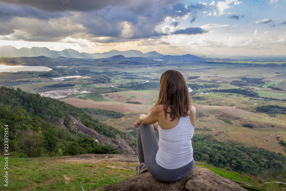 Naklejka premium woman sitting on top of mountain