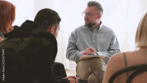 Professional psychotherapist talking with young rebellious people during meeting