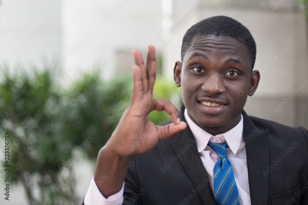 african businessman giving ok hand gesture; portrait of successful confident african business man showing success ok or okay gesture for winner, successful business deal; young adult african man model african businessman giving ok hand gesture; portrait of successful confident african business man showing success ok or okay gesture for winner, successful business deal; young adult african man model