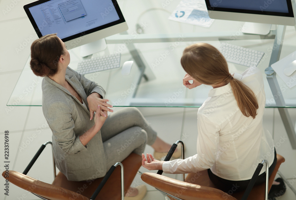 Obraz premium view from the top rear.business woman talking with a colleague sitting near the desktop