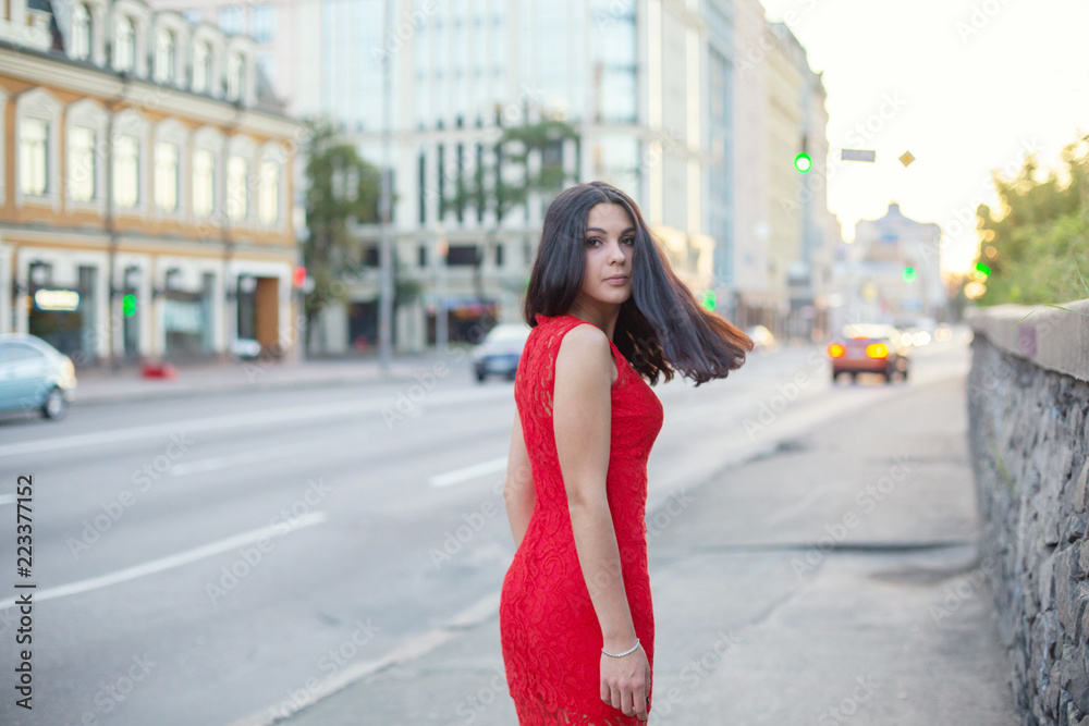Beautiful Girl in a red dress is standing near of the roadway. Beautiful Girl in a red dress is standing near of the roadway.