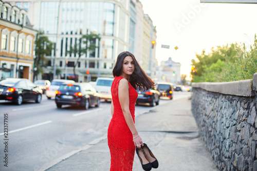 Beautiful Girl in a red dress is standing near of the roadway. © Roman Rvachov