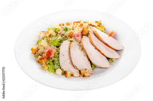 Caesar salad with slices of chicken breast, rusks, tomato, lettuce, cheese on plate, white isolated background Side view. For the menu, restaurant, bar, cafe