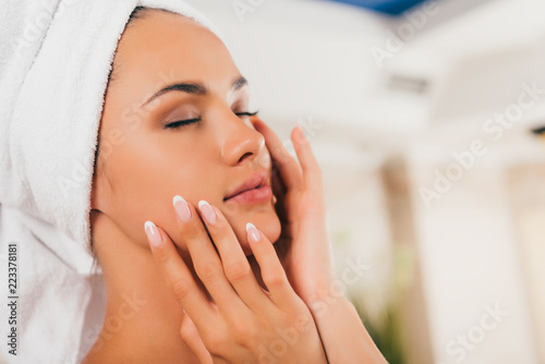 attractive woman in towel on head touching perfect clean face