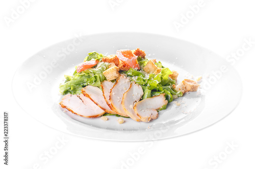 Caesar salad with slices of chicken breast, rusks, tomato, lettuce, cheese on plate, white isolated background Side view. For the menu, restaurant, bar, cafe
