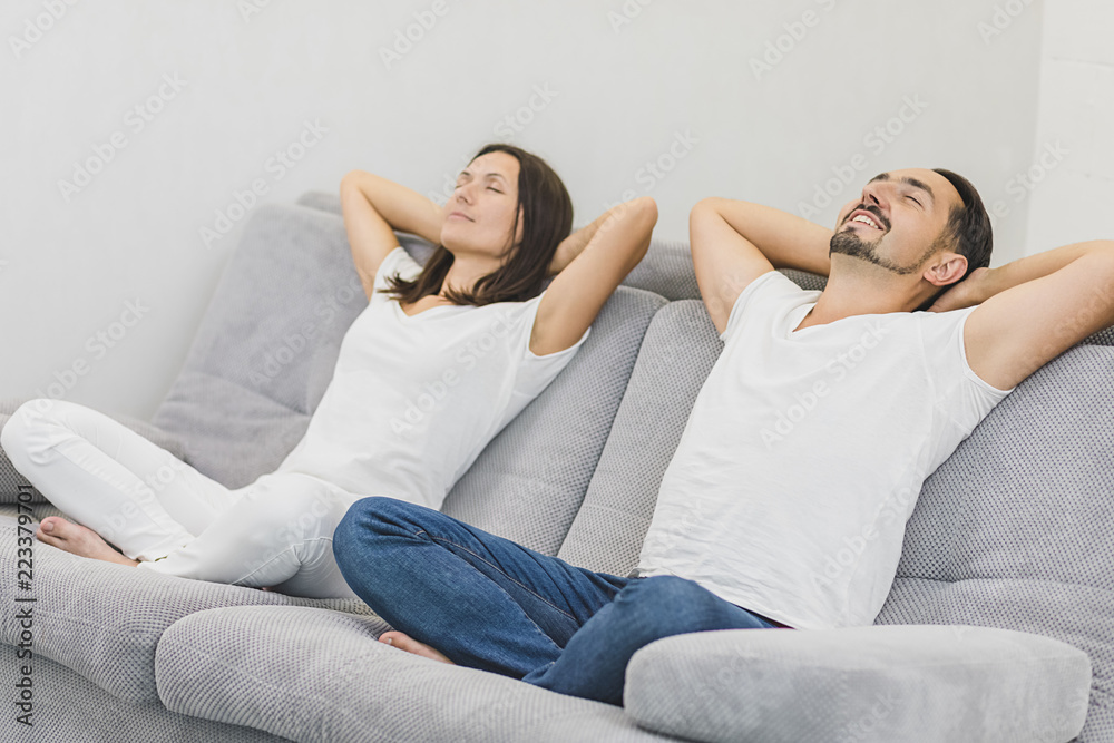 Happy couple relaxing on the couch at home in the living room. Side view Happy couple relaxing on the couch at home in the living room. Side view