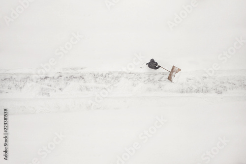 janitor cleans the snow-covered parking space during the snow season. Winter time.