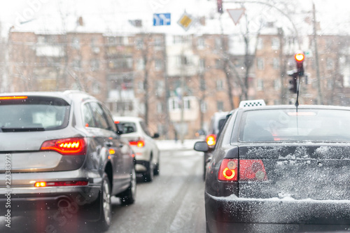 Cars standing in row in traffic jam on city street on slippery snowy road in winter. Vehicles get stuck on road during rush hour at cold winter season. Weather forecast