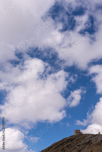 Rifugio sulla cima della montagna con cielo azzurro con nuvole bianche 