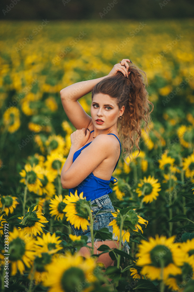 Young beautiful woman in a dress among blooming sunflowers. Agro-culture. Young beautiful woman in a dress among blooming sunflowers. Agro-culture.
