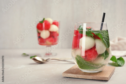 Glass with tasty melon and watermelon ball drink on gray table