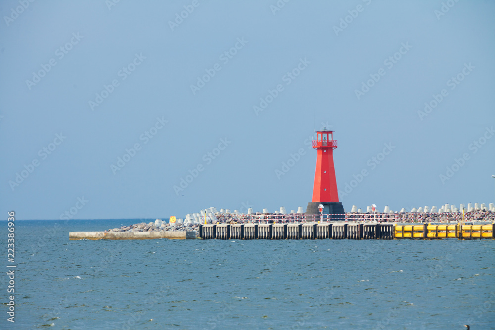 Red lighthouse on promenade near sea