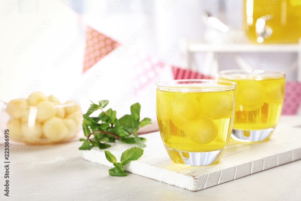 Fototapeta premium Glasses with tasty melon ball drink on light table