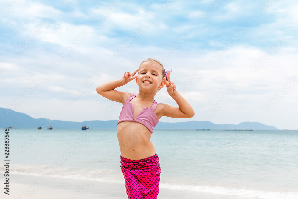 Little beautiful girl dressed in swimsuit as a mermaid stay on the seashore Little beautiful girl dressed in swimsuit as a mermaid stay on the seashore