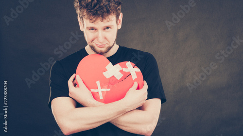 Sad man with glued heart by plaster. photo