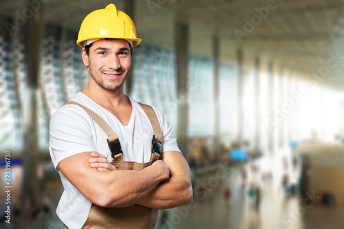 Young builder in hardhat on blurred construction photo