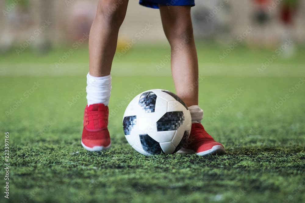 Traditional soccer ball on soccer field grass with young player feet