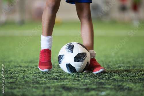 Fototapeta Naklejka Na Ścianę i Meble -  Traditional soccer ball on soccer field grass with young player feet