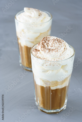 Ice coffee topped with vanilla ice cream, whipped cream and grated chocolate. Gray table, high resolution.