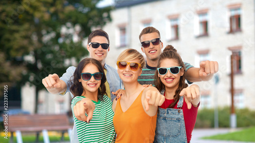 education, choice and people concept - group of happy smiling friends in sunglasses pointing at you over school or campus background
