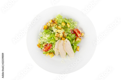 Caesar salad with slices of chicken breast, rusks, cherry tomato, lettuce, cheese on plate, white isolated background, view from above, for the menu, restaurant, bar, cafe