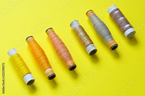 yellow thread reels for sewing on a yellow background. photo thread on. threads of shades of yellow. sewing, needlework, handmade. Use for backgrounds, wallpapers, posters, advertisements, card