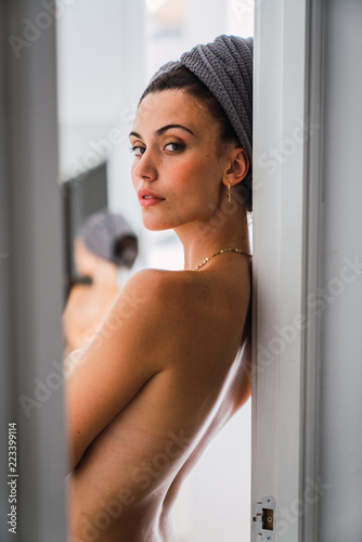 Young topless woman standing in front of mirror photo