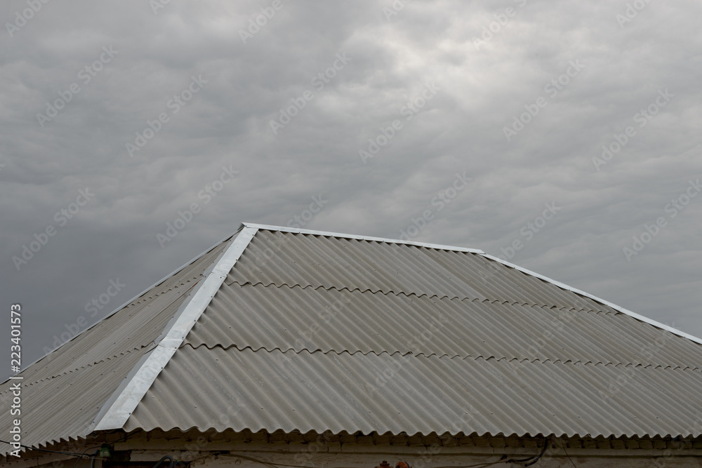 Asbestos-cement wave sheet roof on cloudy sky background. Asbestos-cement wave sheet roof on cloudy sky background.