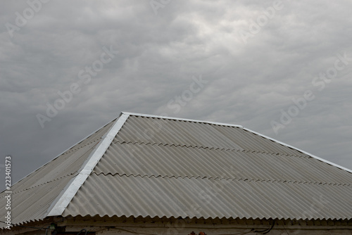 Asbestos-cement wave sheet roof on cloudy sky background.