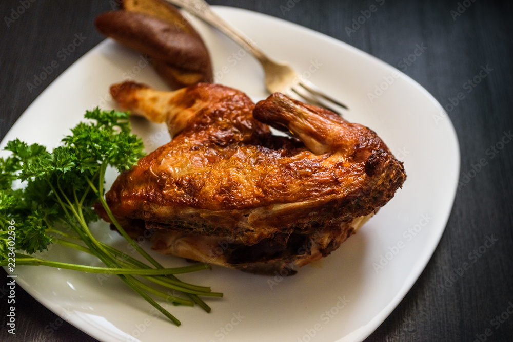 baked chicken on a plate, on a black background baked chicken on a plate, on a black background