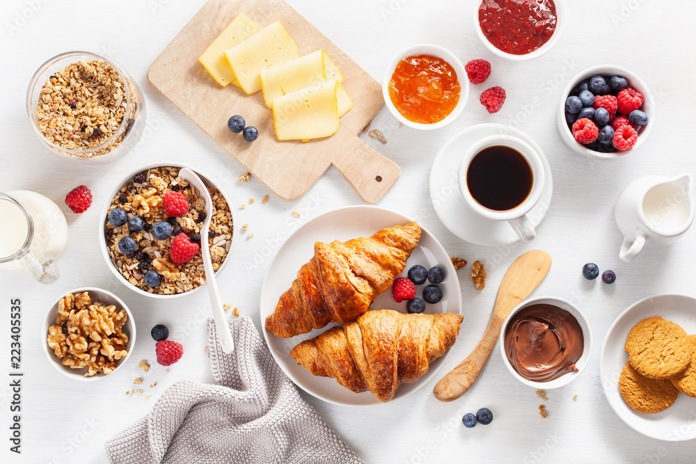 healthy breakfast with granola, berry, nuts, croissant, jam, chocolate spread and coffee. Top view