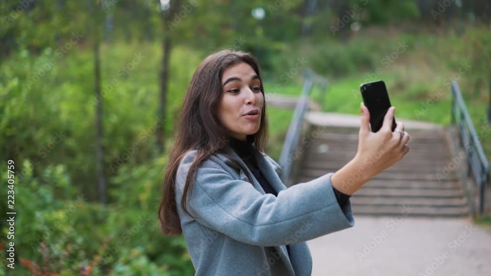 Happy young woman sending sms, texting in the park Happy young woman sending sms, texting in the park