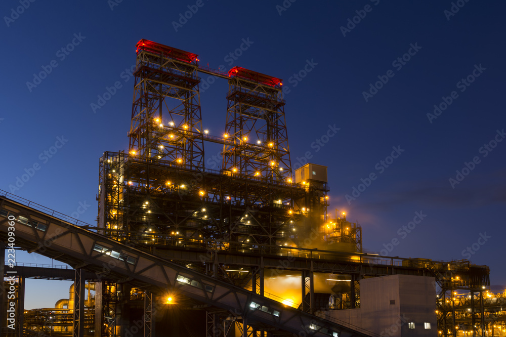 Night industrial landscape with bright lights of lanterns - 4-drum delayed coking unit in a petroleum refinery Night industrial landscape with bright lights of lanterns - 4-drum delayed coking unit in a petroleum refinery