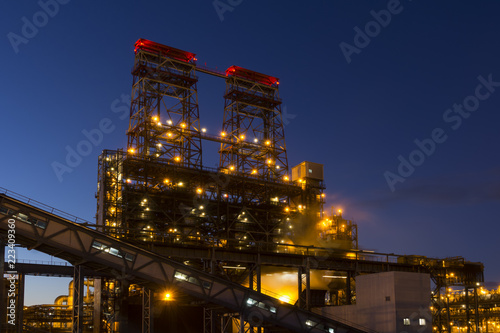 Night industrial landscape with bright lights of lanterns - 4-drum delayed coking unit in a petroleum refinery
