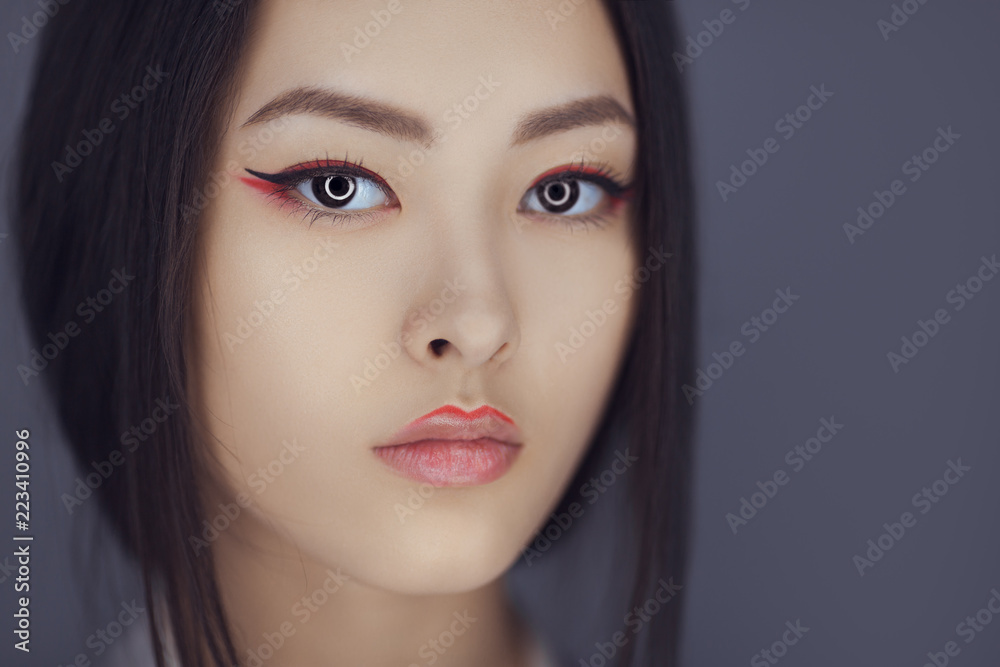Serious asian beauty woman skin care close-up. Beautiful young girl with  perfect skin face looking at camera. Isolated on gray background. Tender  sensual mixed race Asian Caucasian female in studio foto de