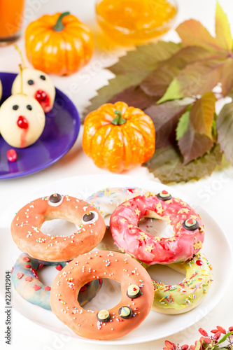Halloween donuts with pumpkin juice and autumn leaves.