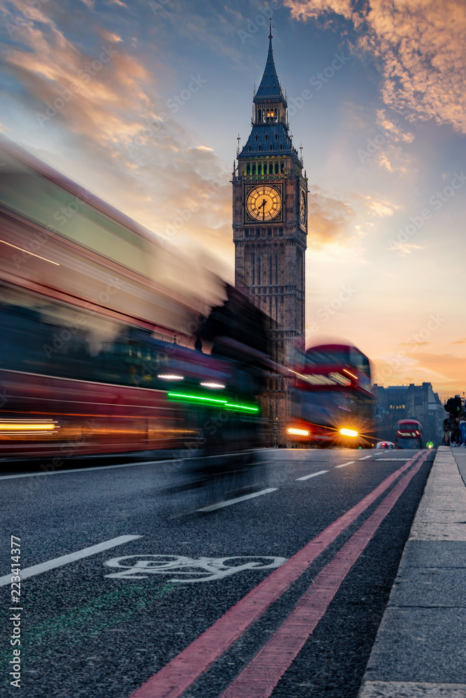 Der Big Ben Turm in London bei Sonnenuntergang und Rushhour mit vorbeifahrendem Bus 