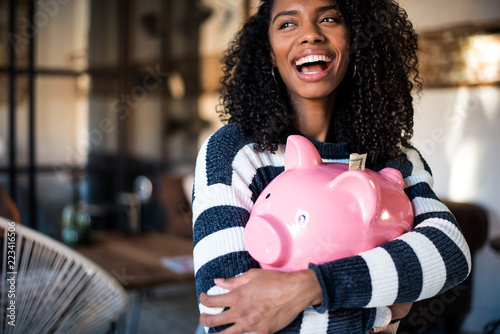 Black woman hugging her piggy bank photo