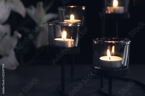 Burning candles on dark background. Funeral symbol
